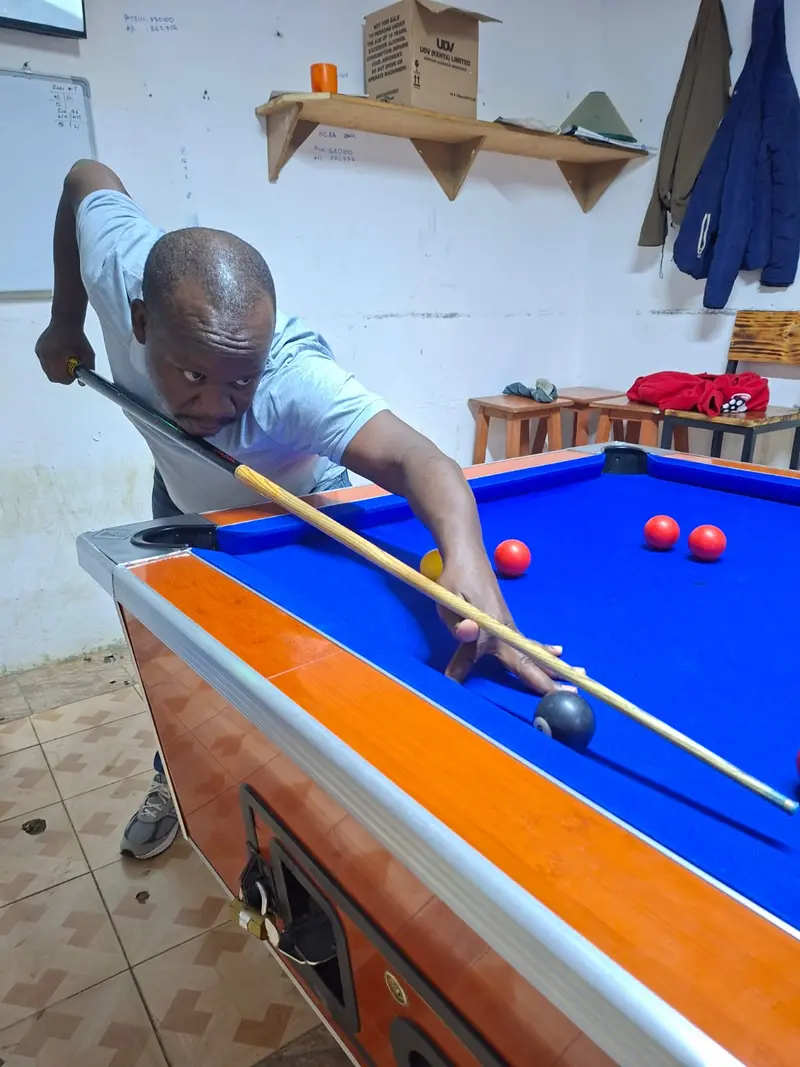 A player lines up a shot along the rail with the black 8-ball close to his bridge hand.